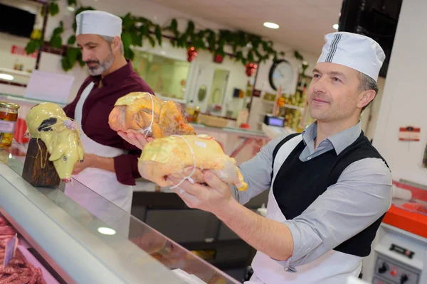 Açougueiro segurando um pedaço inteiro de frango — Fotografia de Stock