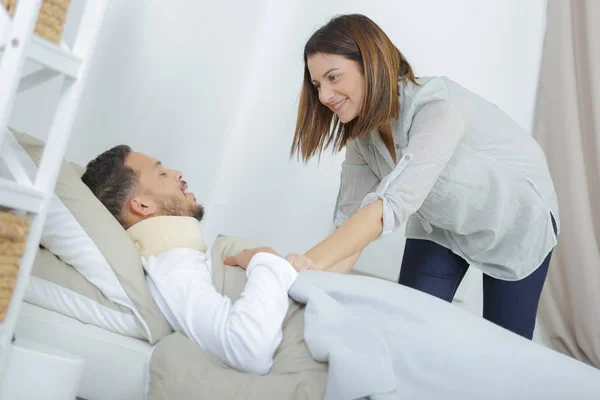Nainen hoitaa sairas poikaystävä sängyssä — kuvapankkivalokuva