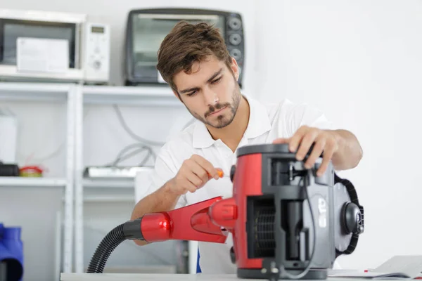 Apuesto joven reparador fijación aspiradora —  Fotos de Stock