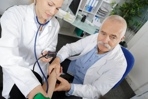 Jovem médico aprendendo a testar pacientes pressão arterial — Fotografia de Stock
