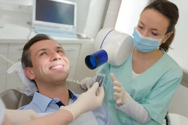 Dentista femenino con paciente masculino en el consultorio dental — Foto de Stock