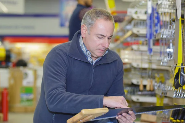 Homem comprando serra manual na loja de ferragens — Fotografia de Stock