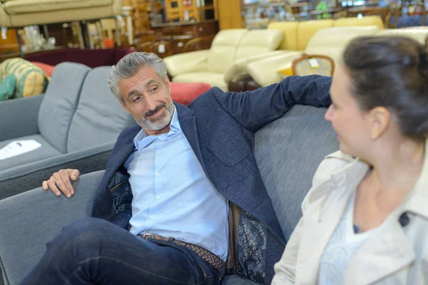 Couple sitting on sofa in furniture store — Stock Photo, Image