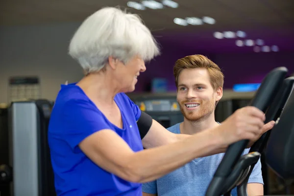 Mujer mayor haciendo ejercicios con el entrenador — Foto de Stock