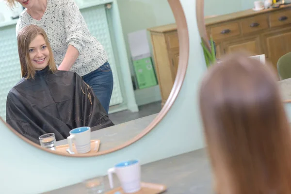 Pozitivní žena stříhá vlasy dívky v salonu — Stock fotografie