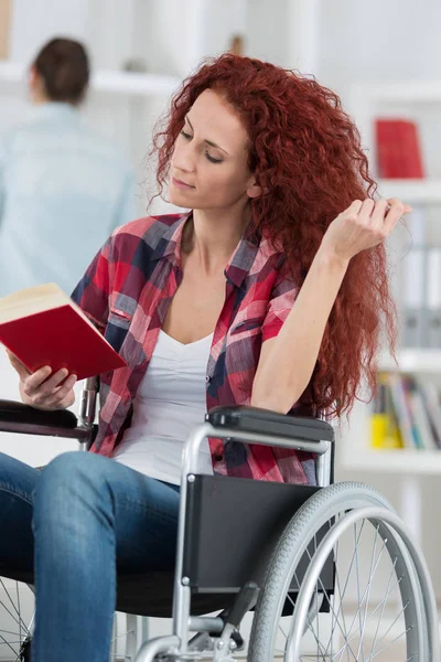 Mulher deficiente feliz sentado em leitura de cadeira de rodas — Fotografia de Stock