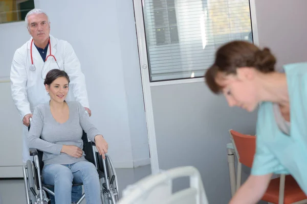 Доктор штовхає пацієнта в інвалідне крісло — стокове фото