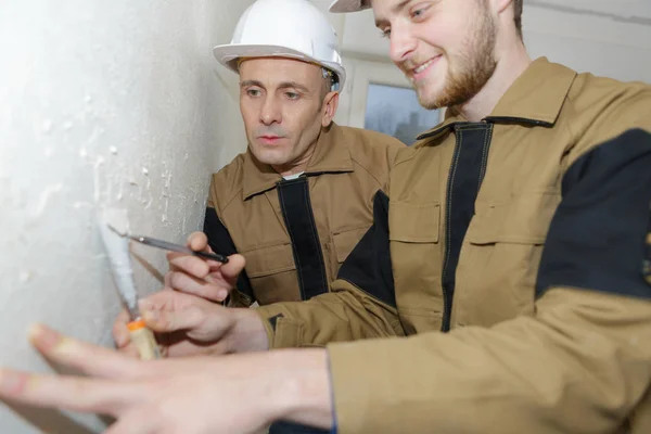 Jonge stukadoor en manager bezig binnen muur — Stockfoto