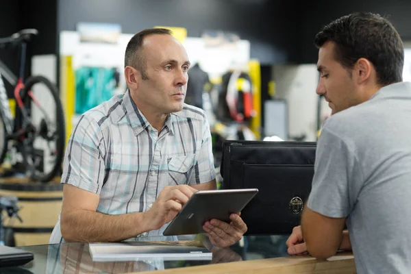 Venditore negozio di biciclette utilizzando tablet digitale per riempire l'ordine dei clienti — Foto Stock