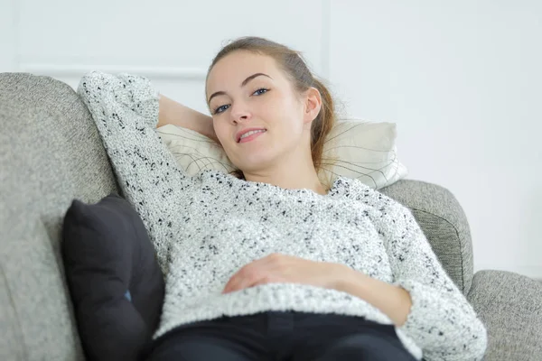 Красива молода жінка розслабляється на дивані вдома — стокове фото