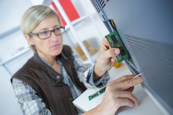 Glückliche Frau repariert Computer am Schreibtisch bei der Arbeit — Stockfoto