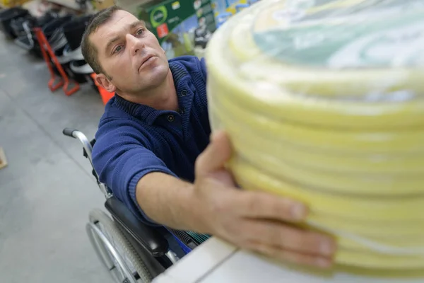 Homme dans un fauteuil roulant acheter conduit tuyau en nylon — Photo