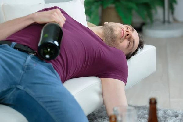 Człowiek śpi, trzymając butelkę alkoholu — Zdjęcie stockowe