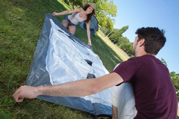 Feliz jovem casal montar sua tenda no local de acampamento — Fotografia de Stock