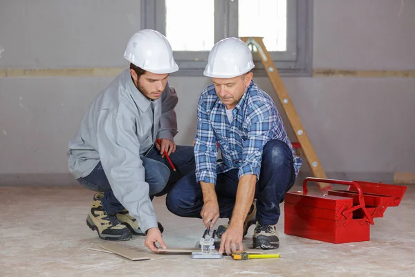 Constructores poniendo las baldosas en el suelo — Foto de Stock