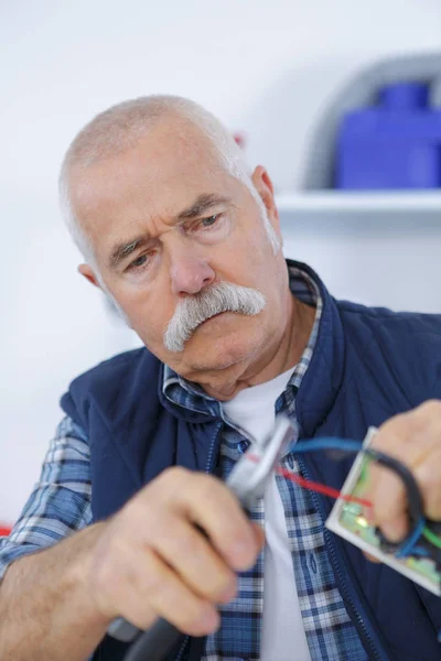 Alter Senior schneidet Draht per Zange von Hand — Stockfoto