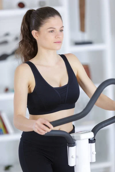 Chica en casa en la máquina de ejercicio —  Fotos de Stock