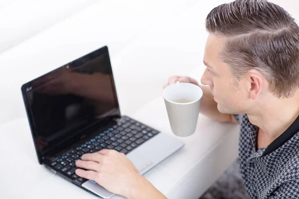 Knappe zakenman met behulp van een laptop en koffie drinken — Stockfoto