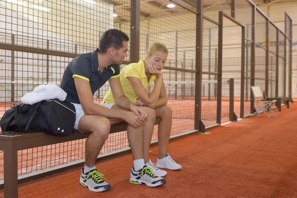男性のテニス プレーヤーが苦しめられた女性のパートナーを落ち着かせ — ストック写真