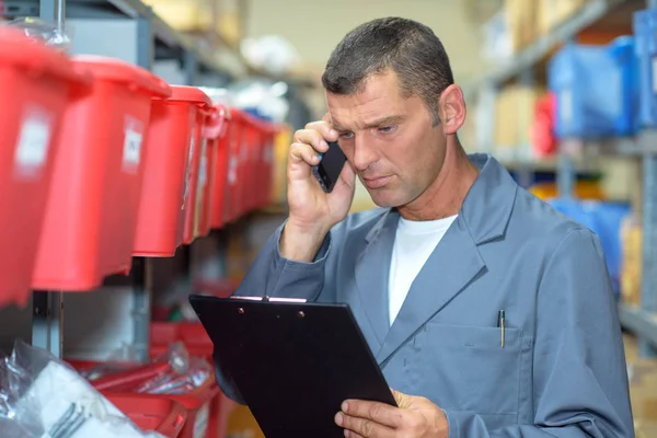 Man in magazijn op telefoon op zoek betrokken — Stockfoto