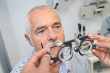 ophthalmologist precisely determines diopter for senior man clipart