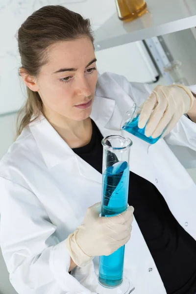 Investigadora científica está mirando el tubo en el laboratorio —  Fotos de Stock