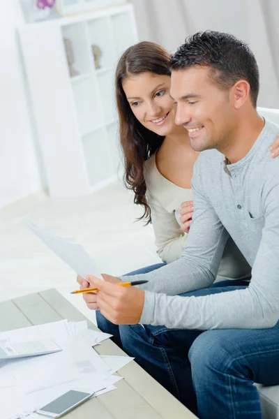 Couple souriant avec des documents à la maison — Photo