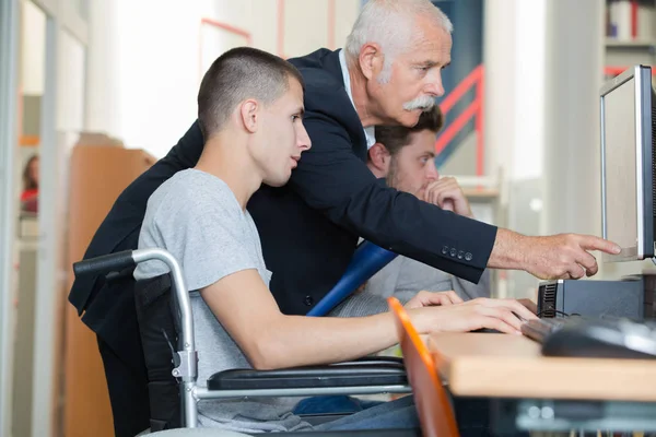 Étudiant en fauteuil roulant parlant avec un camarade de classe à la bibliothèque — Photo