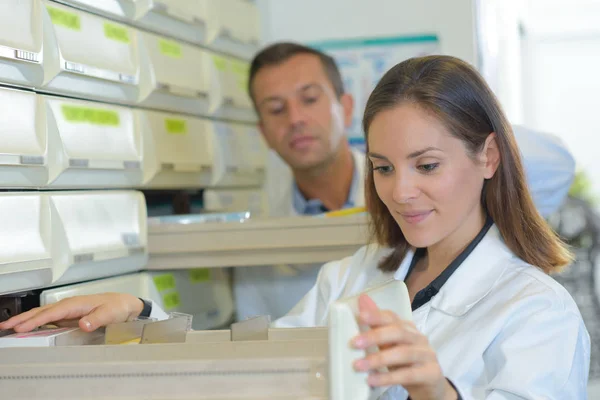 Farmacistas olhando em gavetas — Fotografia de Stock