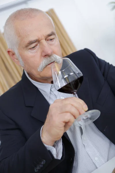 Odore sommelier maturo a un bicchiere di un vino rosso — Foto Stock