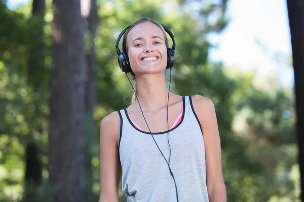 Young woman listening music with headphone in nature — Stock Photo, Image