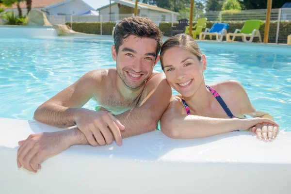 Casal inclinado no lado da piscina — Fotografia de Stock