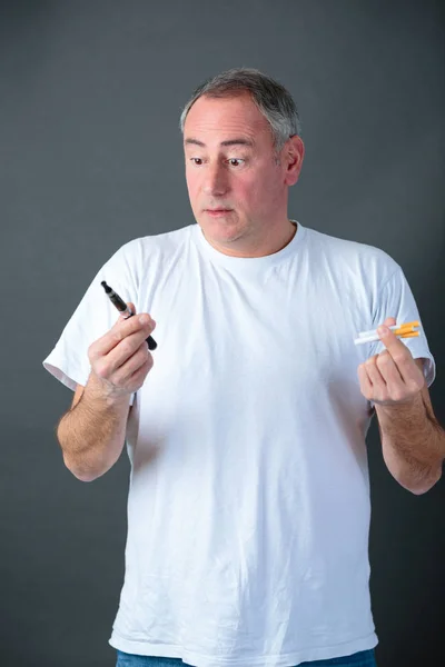 Man is holding vaporizer and conventional tobacco cigarettes and comparing — Stock Photo, Image