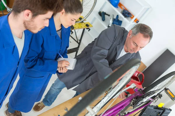 Cyklistický mechanik a učeň oprava kola v dílně — Stock fotografie