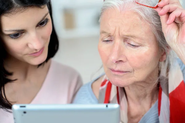 Hilfe für alte Frau beim Umgang mit einem Tablet-Computer — Stockfoto