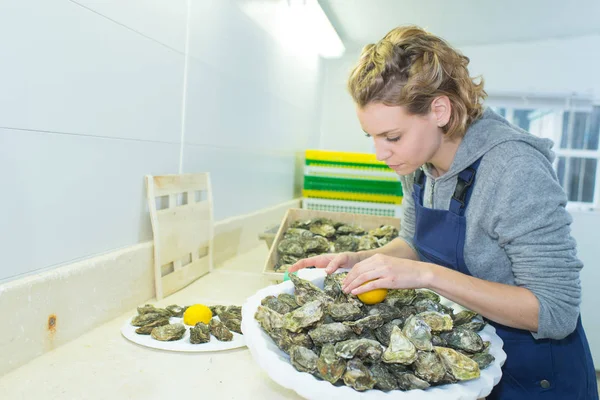Vrouwelijke voorbereiding van een grote lade van oesters — Stockfoto