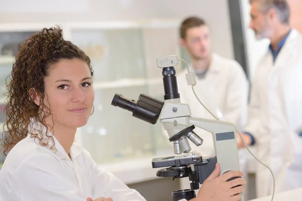 Científica femenina que mira al microscopio — Foto de Stock