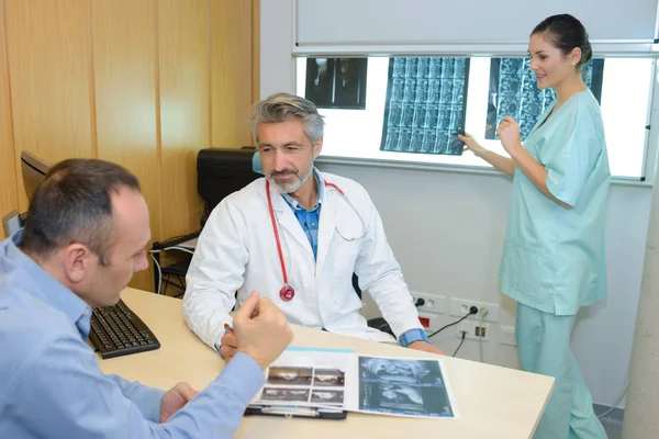 Медицинские работники обсуждают рентген с пациентом — стоковое фото