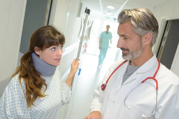 Patient med hals stag och bärbara dropp prata med läkare i korridor — Stockfoto