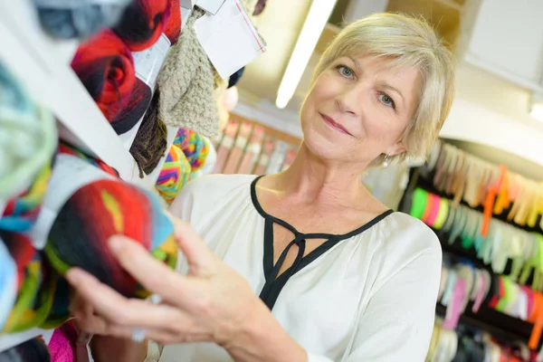 Lady taking ball of wool from shelf — Stock Photo, Image