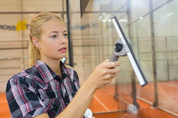 Hübsche Frau putzt Fenster im Squash-Club — Stockfoto