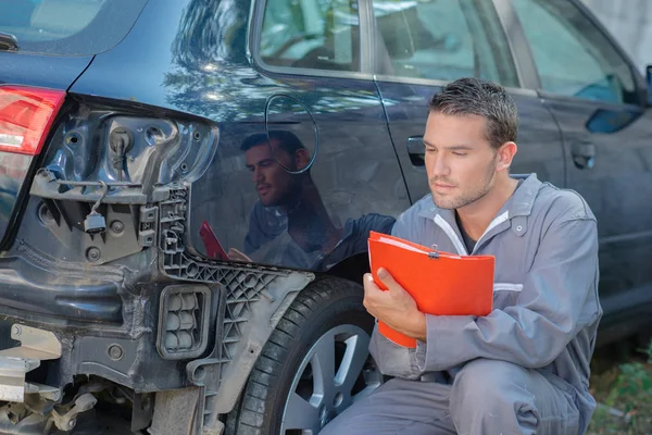 Mechaniker inspiziert beschädigtes Auto — Stockfoto