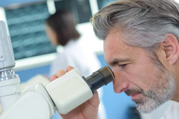 Científico examinando la muestra con microscopio en el laboratorio —  Fotos de Stock