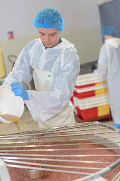 Genç adam girişi karıştırıcı gıda fabrikasında sıvı dökme — Stok fotoğraf