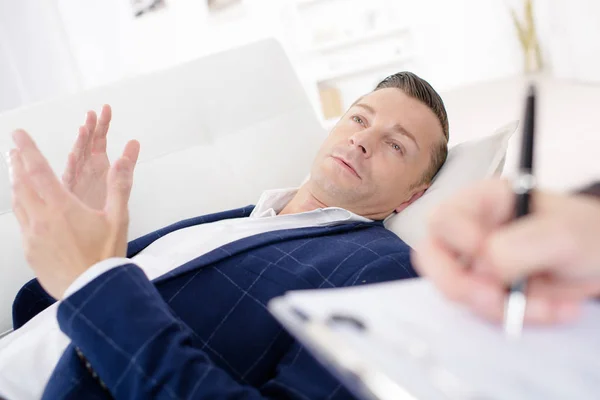 Zakenman die op een bank in gesprek met zijn psychiater te leggen — Stockfoto