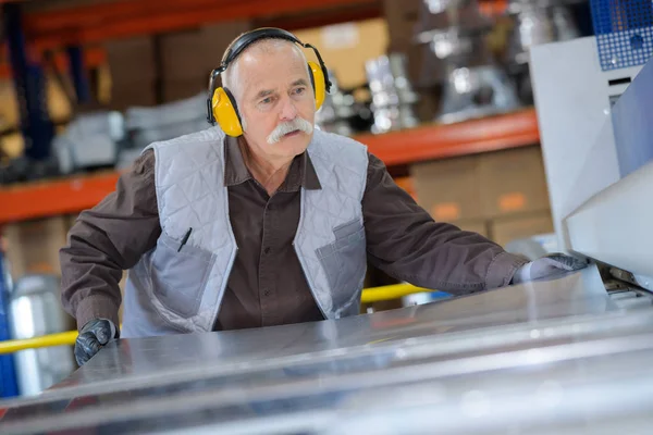 Senior ambachtsman werken met arbeid bescherming bij timmerwerk shop — Stockfoto