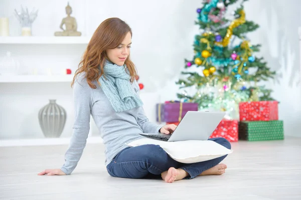 Femme assise jambes croisées sur le sol, ordinateur portable sur ses genoux — Photo