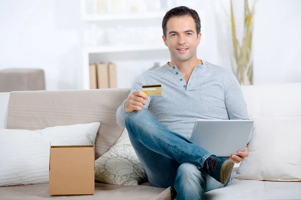 Portrait of man at home holding laptop and credit card — Stock Photo, Image