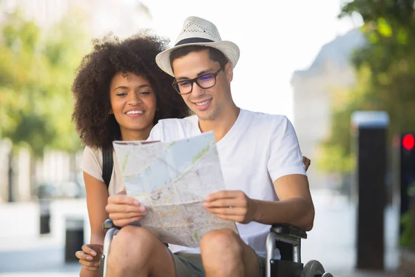 Jonge man op de rolstoel die houden van een kaart — Stockfoto