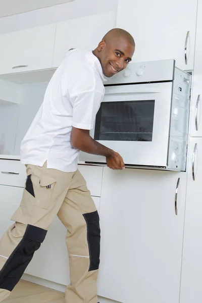 Mann baut Ofen in Küche ein — Stockfoto